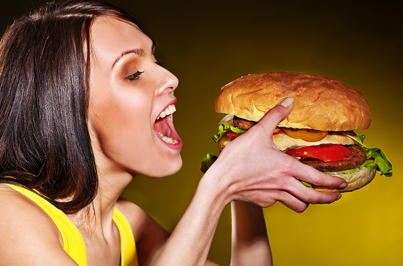 woman holding an oversized hamburger with both hands