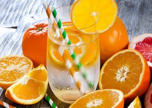 glass of orange infused water surrounded by orange slices