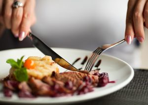 Woman eating a healthy home cooked steak with a side of vegetables
