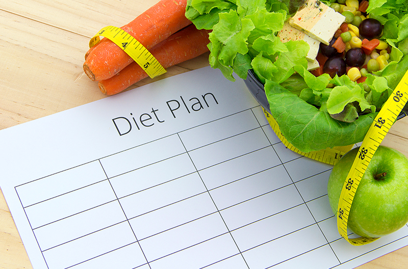 A diet plan piece of paper with a salad, apple, and bunch of carrots