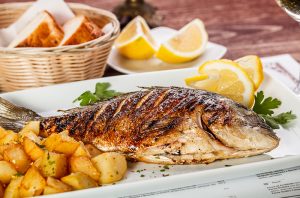 grilled whole fish with potatoes and lemon wedges