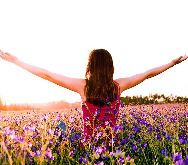 woman standing in a field of flowers with outstretched arms