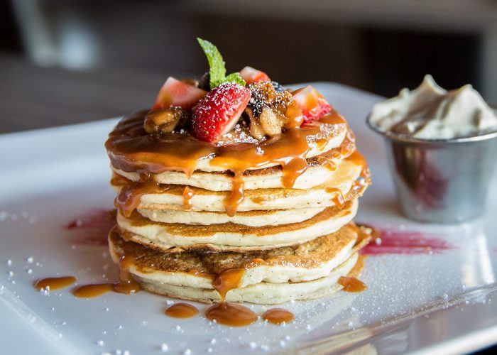 stack of pancakes topped with berries and syrup
