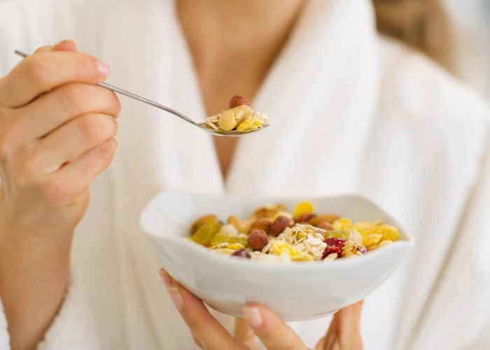 woman eating a healthy breakfast of cereals and nuts
