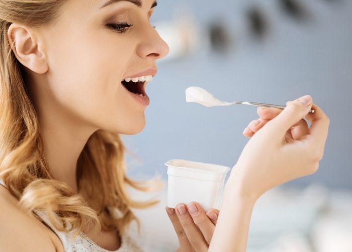 Side profile of a woman smiling and eating yogurt