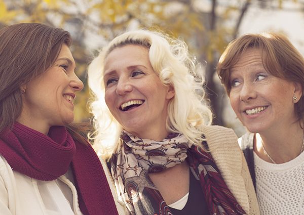 Group of three happy middle-aged women socializing out in a park