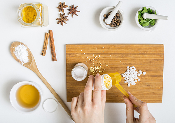 Woman in the middle of making her own DIY beauty products with an assortment of ingredients like honey and star anise on a table