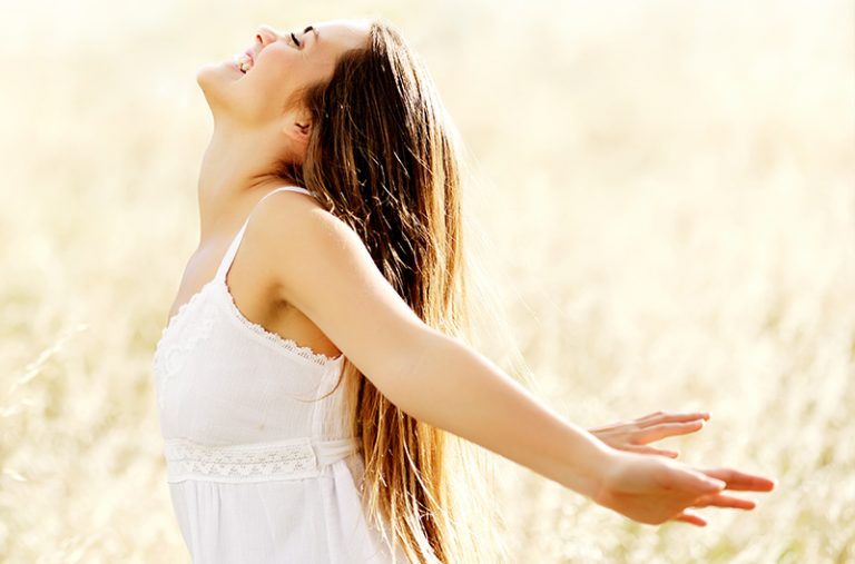 Woman in a field stretching back her arms in happiness
