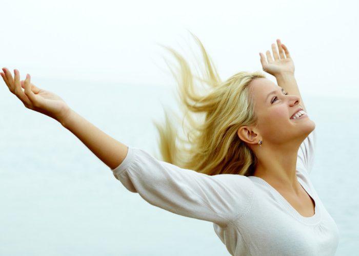 Happy smiling woman with her hands up in the air living life to the fullest