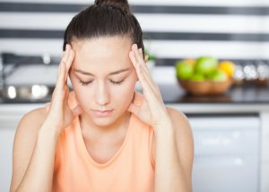 woman having a migraine and holding her head with two hands