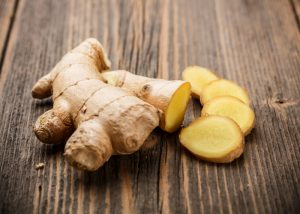 whole ginger and ginger slices on wooden table