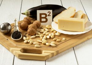 foods rich in vitamin b2 such as eggplant, cheese, almonds, walnuts on cutting board