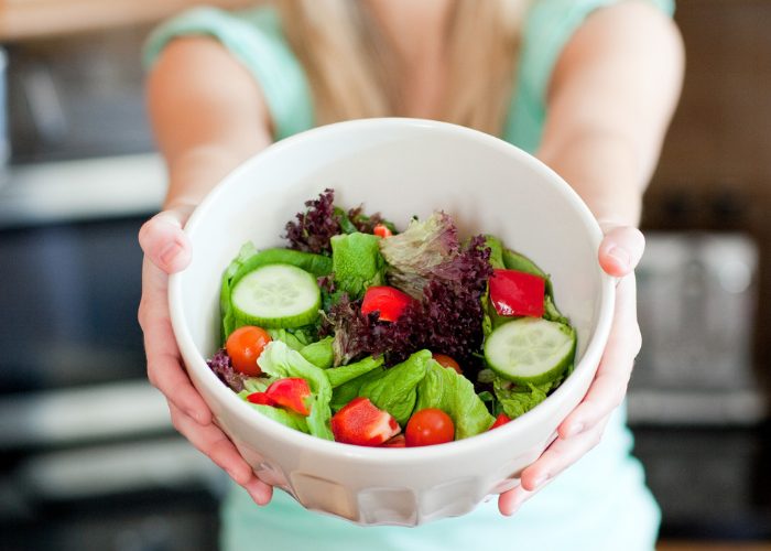 Woman holding out a bowl of salad
