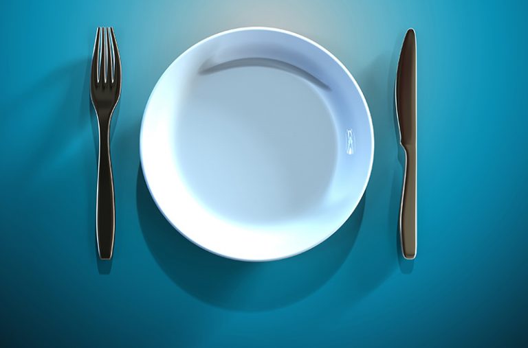 An empty white plate with a fork and knife on the side on a blue table