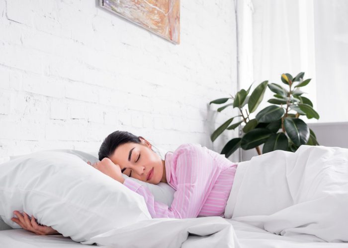 Woman in pink pajamas hugging her pillow as she soundly sleeps