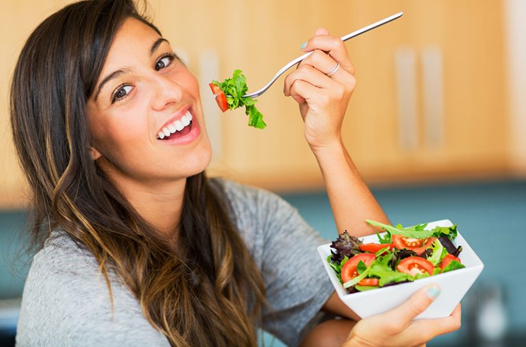 Woman smiling while eating a vegan salad