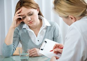 Psychologist taking notes with a female patient who has seasonal affective disorder (SAD)