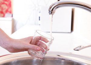 Woman filling up a glass of water in her kitchen sink