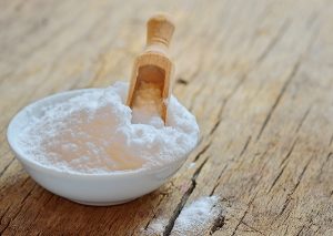 Bowl of baking soda with a wooden scoop 