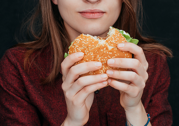 Woman holding a hamburger with a bite taken out of it