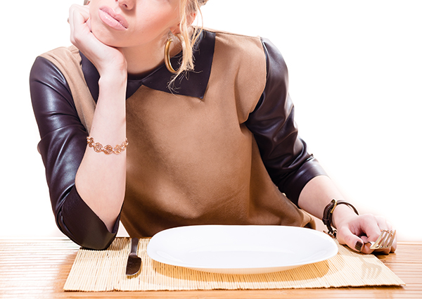 Woman sitting at a restaurant with an empty plate looking hungry