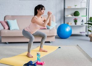 woman doing squats on an exercise mat in a room