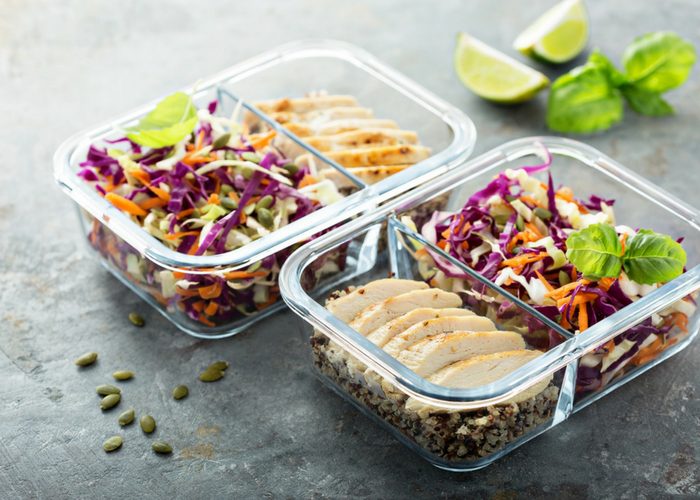 two meal prep containers filled with chicken and salad