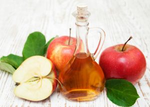 a bottle of apple cider vinegar with red apples 