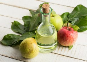 bottle of apple cider vinegar with leaves and apples