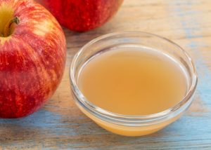 a bowl of filtered apple cider vinegar with two apples