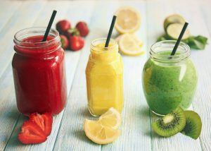 a strawberry, lemon, and kiwi smoothie in jars with straws