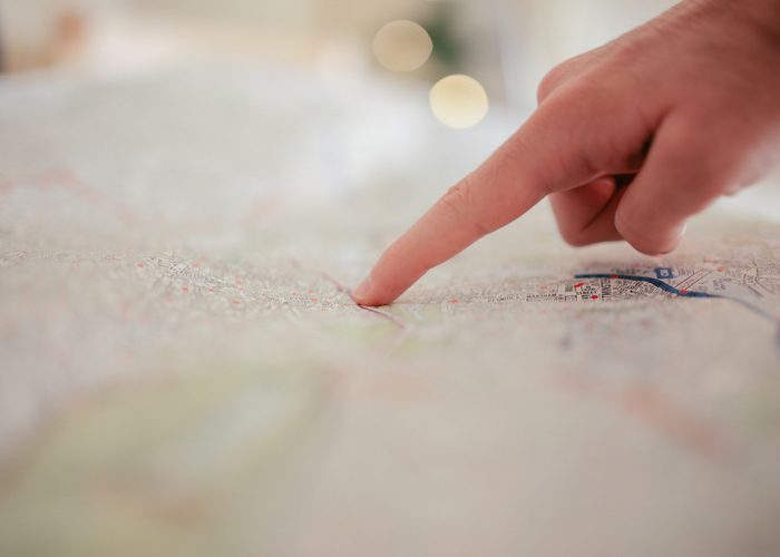 a person's finger pointing at a location on a map
