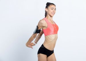 young female in sports wear doing chest stretch standing desk exercises