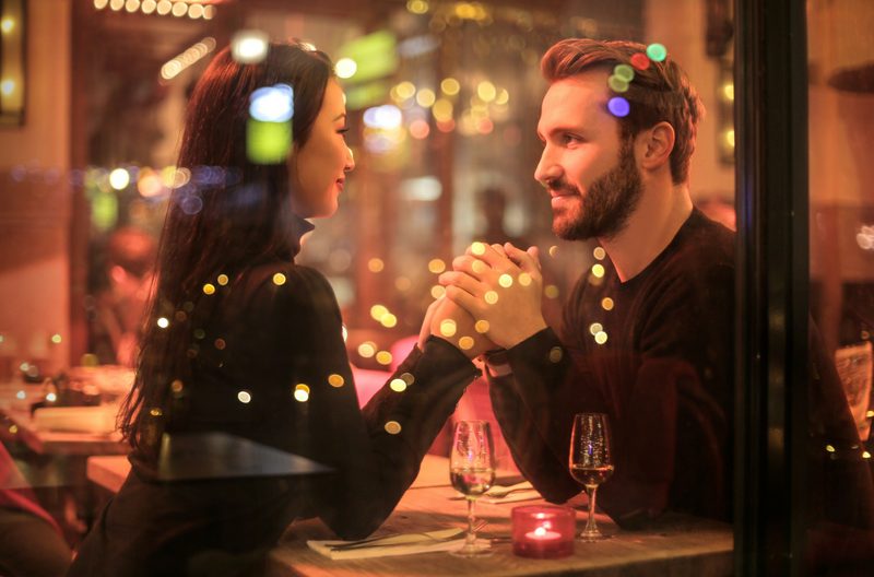 Couple holding hands in a restaurant behind glass pane
