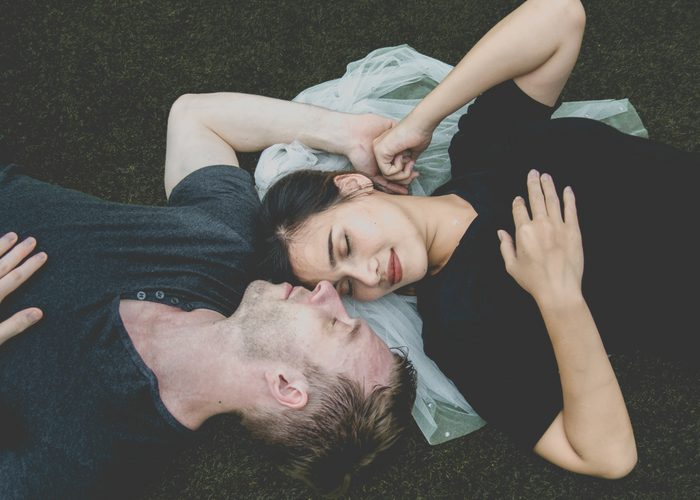 human pheromones attract couple in love lying on grass and holding hands 