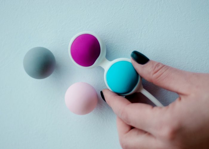 woman holding multicolored kegel balls used for pelvic exercises