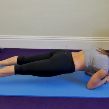 Woman exercising on the floor i plank position in the middle of a lower ab exercises workout