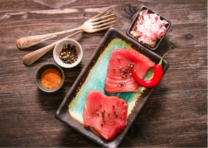 meal kit of raw tuna on plate with condiments and spices on a table 