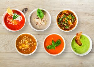 six bowls of healthy colorful soups on a table from meal prep services