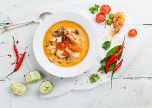 meal prep service delivers spicy thai soup with limes, chili and prawns on a table