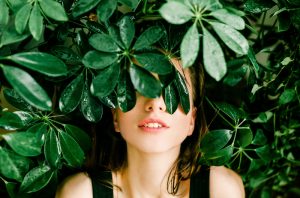 Woman's face covered by green leaves