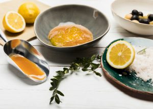 honey, lemons, sea salt and olives on a white table