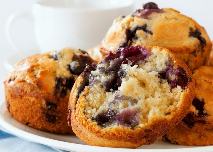 Closeup of freshly baked Paleo blueberry muffins piled on a white plate