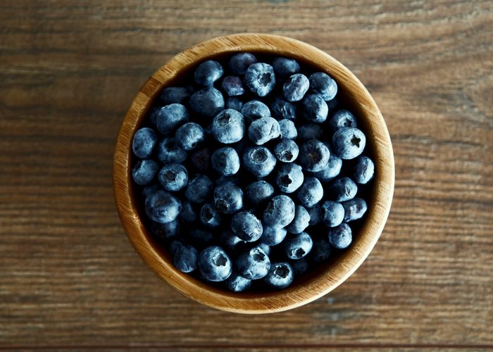 A bowl of fresh blueberries on a wooden table