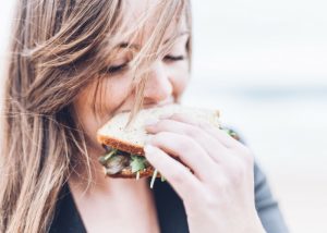 blonde woman biting into a sandwich