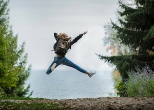 woman jumping while wearing a backpack