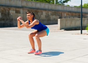 woman doing LIIT body weight squats outside