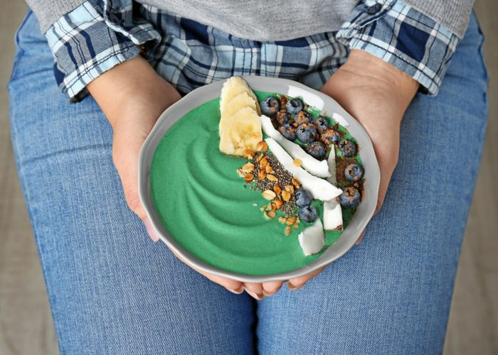 woman holding a spirulina smoothie bowl made with anti cancer foods