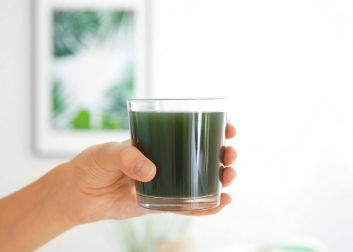 woman's hand holding a glass of spirulina drink