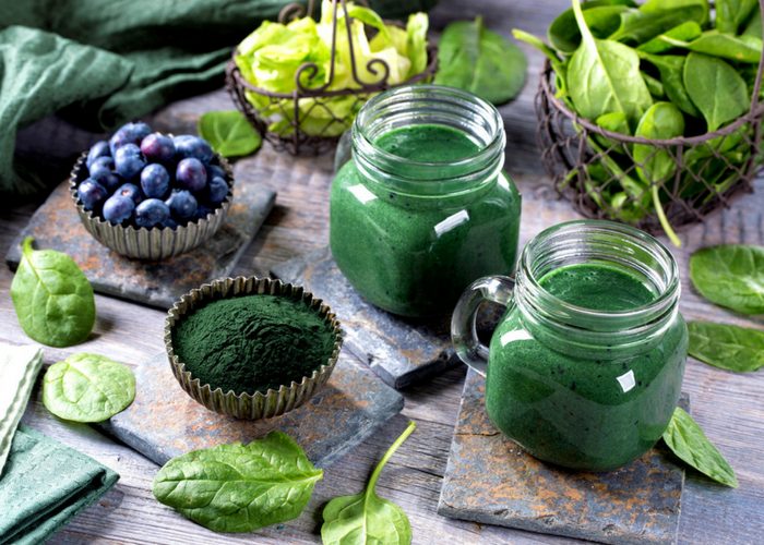 two spirulina smoothies made with anti cancer foods like spinach and blueberries